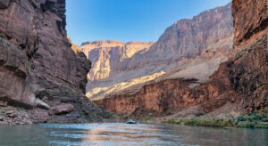 Raft floating through the Grand Canyon on the Colorado River between towering canyon walls
